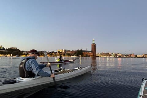 Paddling towards an illumninated skyline in Stockholm with City hall in the background
